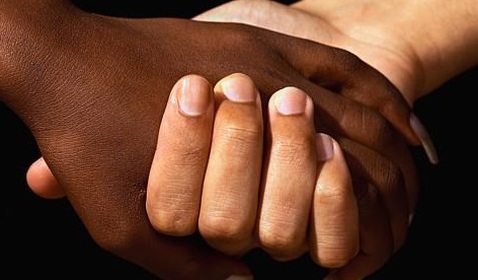 Interracial hands grasping one another